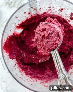 The process of scooping the beet energy ball batter using a cookie dough spoon, ensuring consistent portion sizes.
