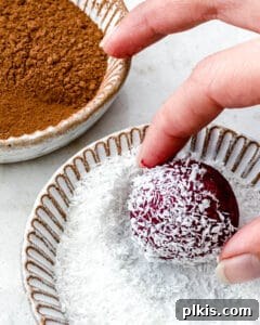 Vibrant Beet Power Bites 9 The process of coating a freshly rolled beet energy ball in a bowl of shredded coconut, adding texture and flavor.
