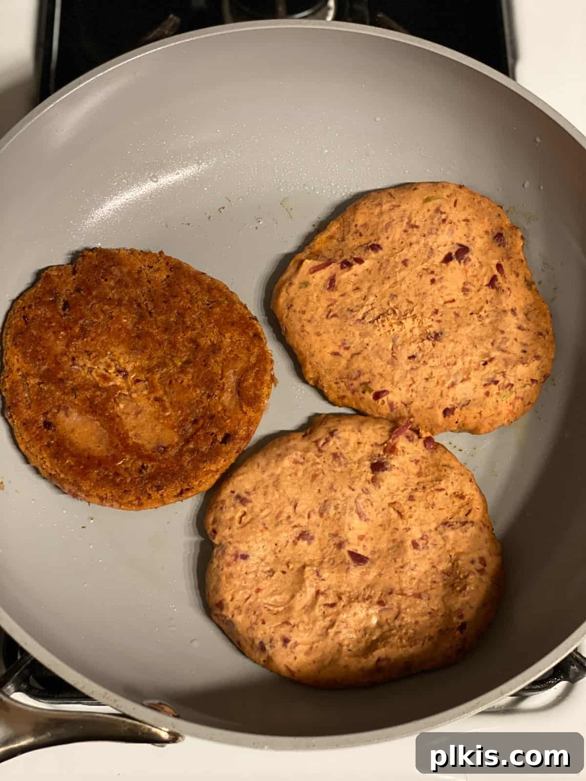 Quick-Fix 4-Ingredient Vegan Burgers 11 Process shot of flipping easy vegan burgers in a hot skillet, showing a crispy golden-brown underside