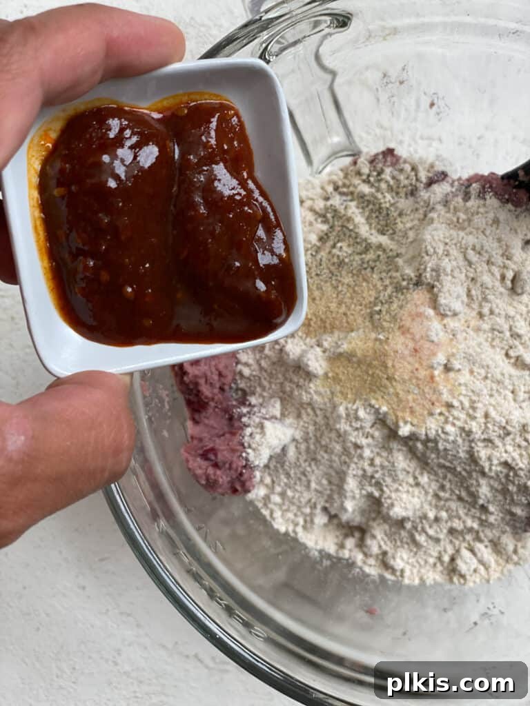 Quick-Fix 4-Ingredient Vegan Burgers 8 Process shot of adding sriracha hot sauce to the burger mixture for a spicy kick