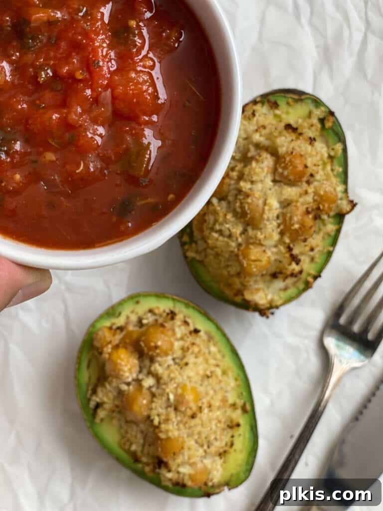 Nutrient-Packed Stuffed Avocado Delights 11 Process shot of fresh salsa being spooned over a stuffed avocado half.