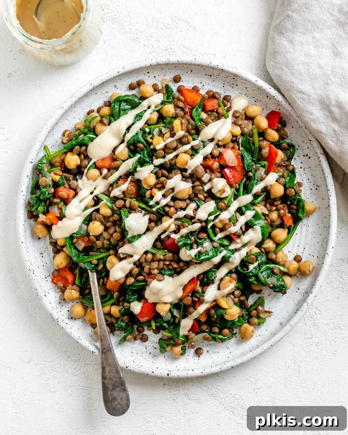 Fresh Lemon Herb Lentil Chickpea Salad 2 Completed Vegan Lentil Chickpea Salad plated on a white plate against a white surface, garnished with fresh herbs.