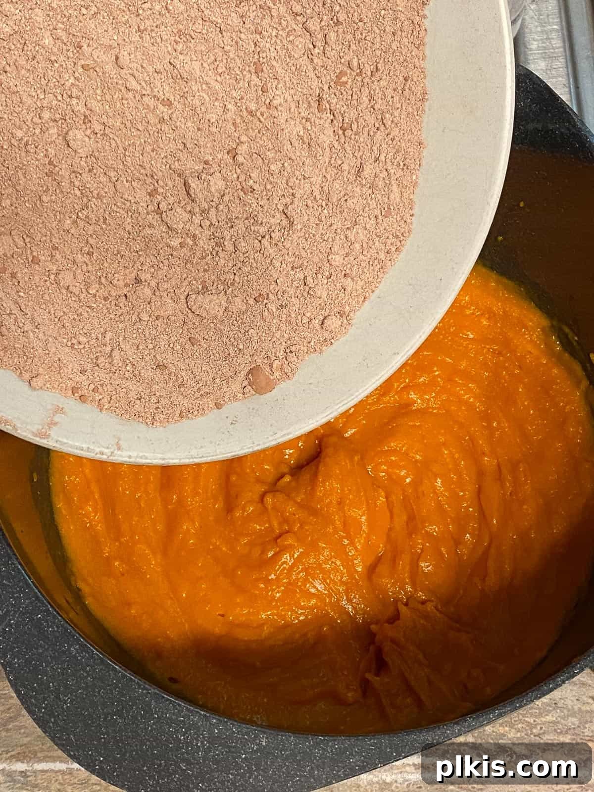 Decadent Sweet Potato Chocolate Cake 8 Process shot of adding cocoa powder to the sweet potato mixture in a bowl