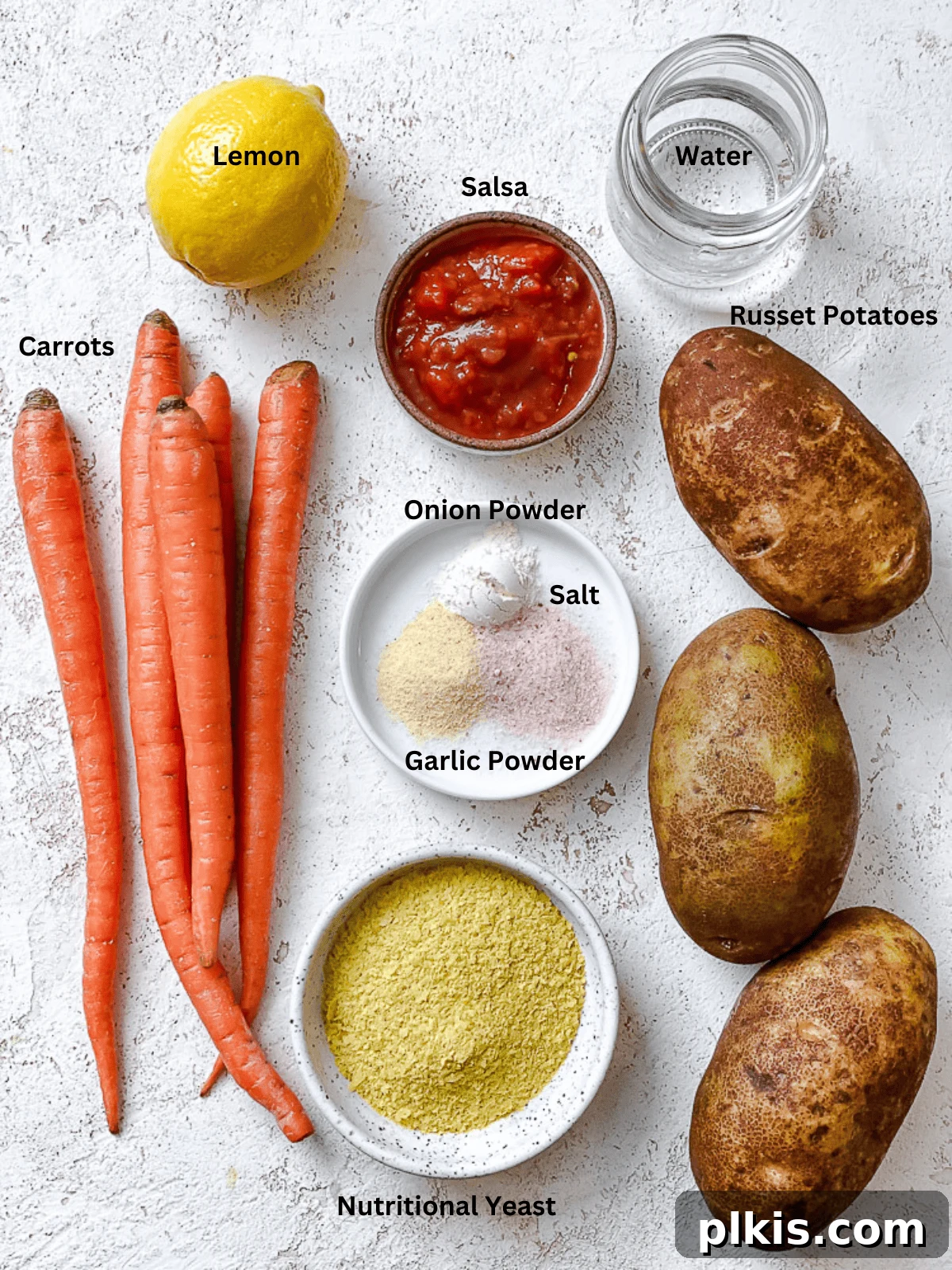 Rich Nacho Cheese Sauce 3 ingredients for vegan nacho cheese sauce with labels, including diced potatoes, sliced carrots, nutritional yeast, salsa, lemon juice, and spices laid out on a wooden board.