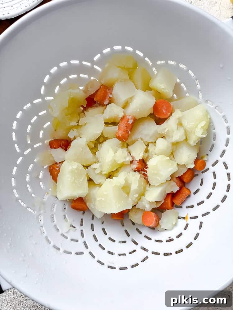 Rich Nacho Cheese Sauce 5 process shot showing boiled and drained potatoes and carrots in a colander after cooking