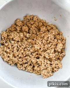 The peanut butter oatmeal mixture is thoroughly combined in a white bowl, forming a cohesive, moldable dough, ready for shaping.
