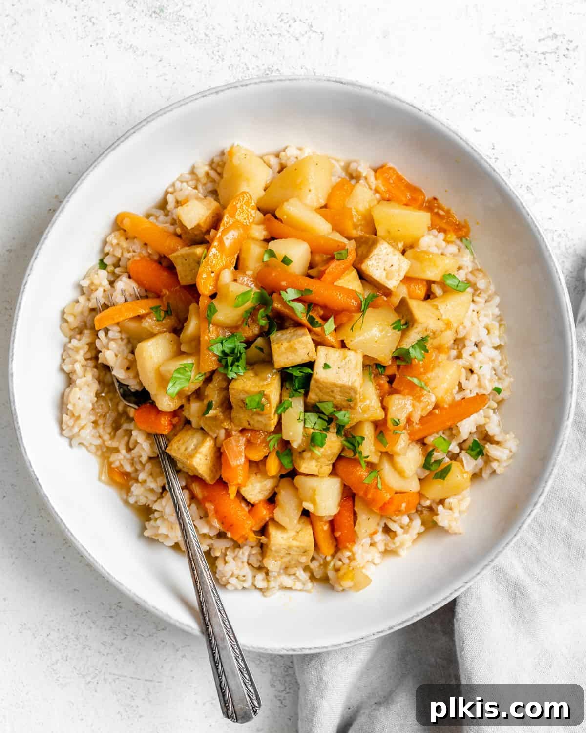 Creamy Red Curry Tofu: Slow Cooker or Stove Top 2 A vibrant bowl of Slow Cooker Red Thai Curry with Tofu, plated elegantly in a white dish against a clean white background, showcasing the creamy texture and colorful vegetables.