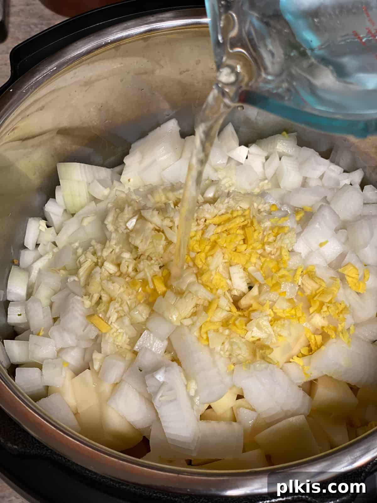 Creamy Red Curry Tofu: Slow Cooker or Stove Top 11 Water being poured into the pan, forming the liquid base for the Slow Cooker Red Thai Curry.