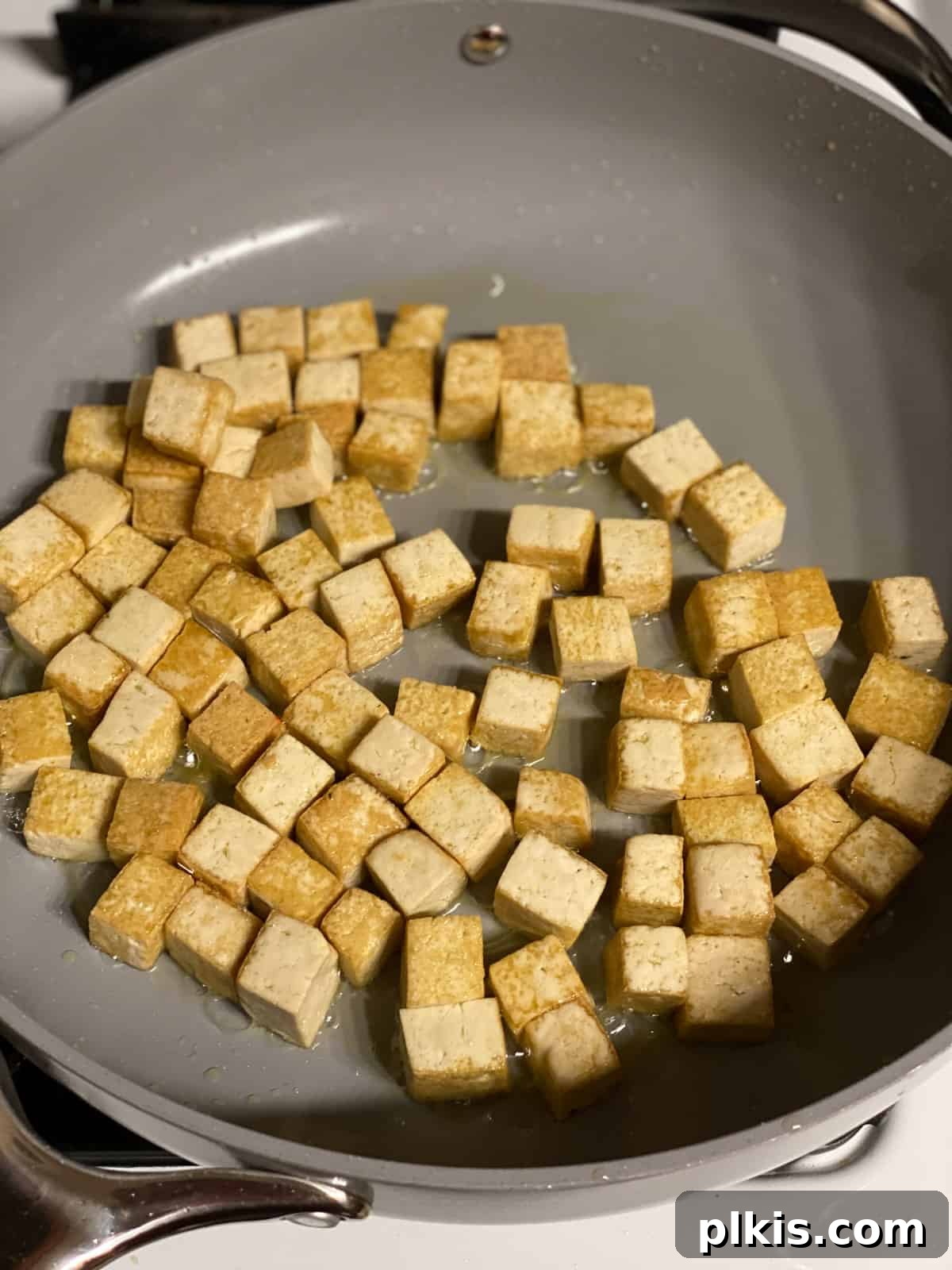 Creamy Red Curry Tofu: Slow Cooker or Stove Top 5 Close-up shot of tofu cubes browning and crisping up in a skillet, capturing the golden-brown edges achieved before adding to the slow cooker for Red Thai Curry.