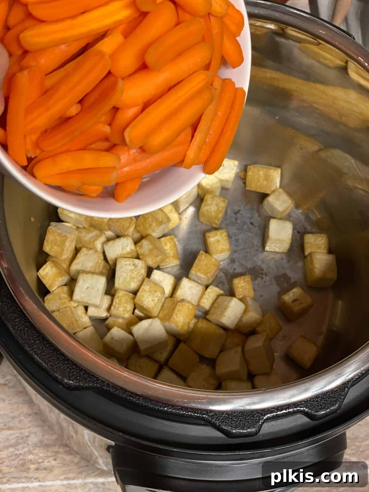 Creamy Red Curry Tofu: Slow Cooker or Stove Top 6 Chopped baby carrots being added to a large pan or slow cooker, preparing for the Red Thai Curry.