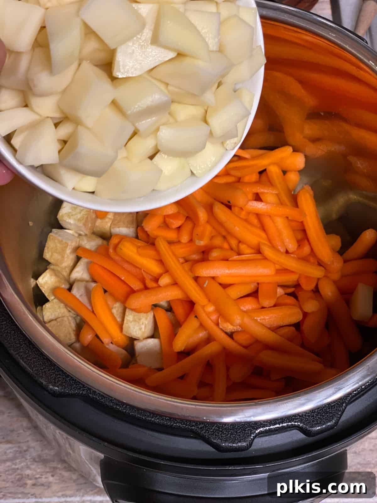 Creamy Red Curry Tofu: Slow Cooker or Stove Top 7 Chopped potatoes being added to the pan, ready to combine with other ingredients for the Red Thai Curry.