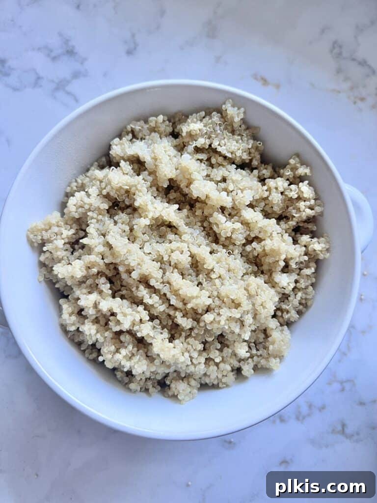 Warm Apple Quinoa Breakfast 4 Close-up of perfectly cooked and fluffed white quinoa in a small white bowl, set against a blurred white marble background, ready for toppings