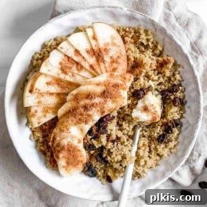completed Breakfast Quinoa Apple Bowl in a white bowl with ingredients scattered in the background