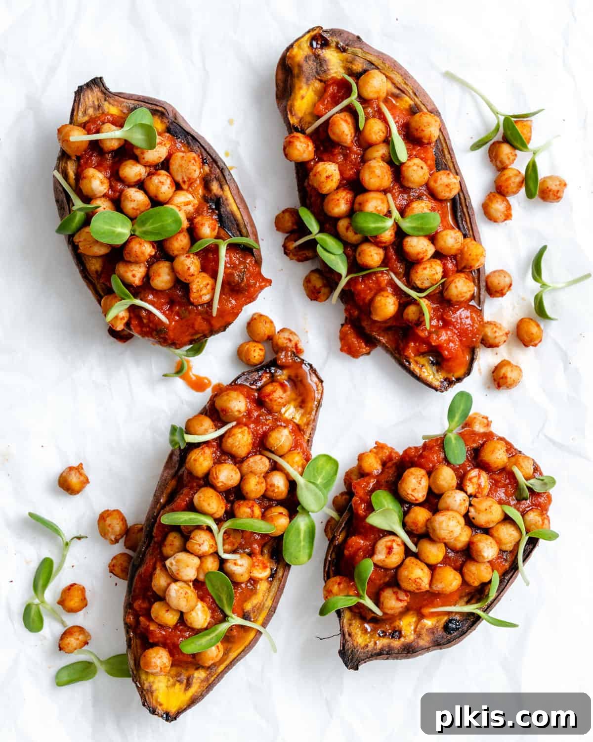 Two completed Chickpea Sweet Potato Boats with fresh sprouts against a clean white surface, showcasing their vibrant colors and appealing texture.