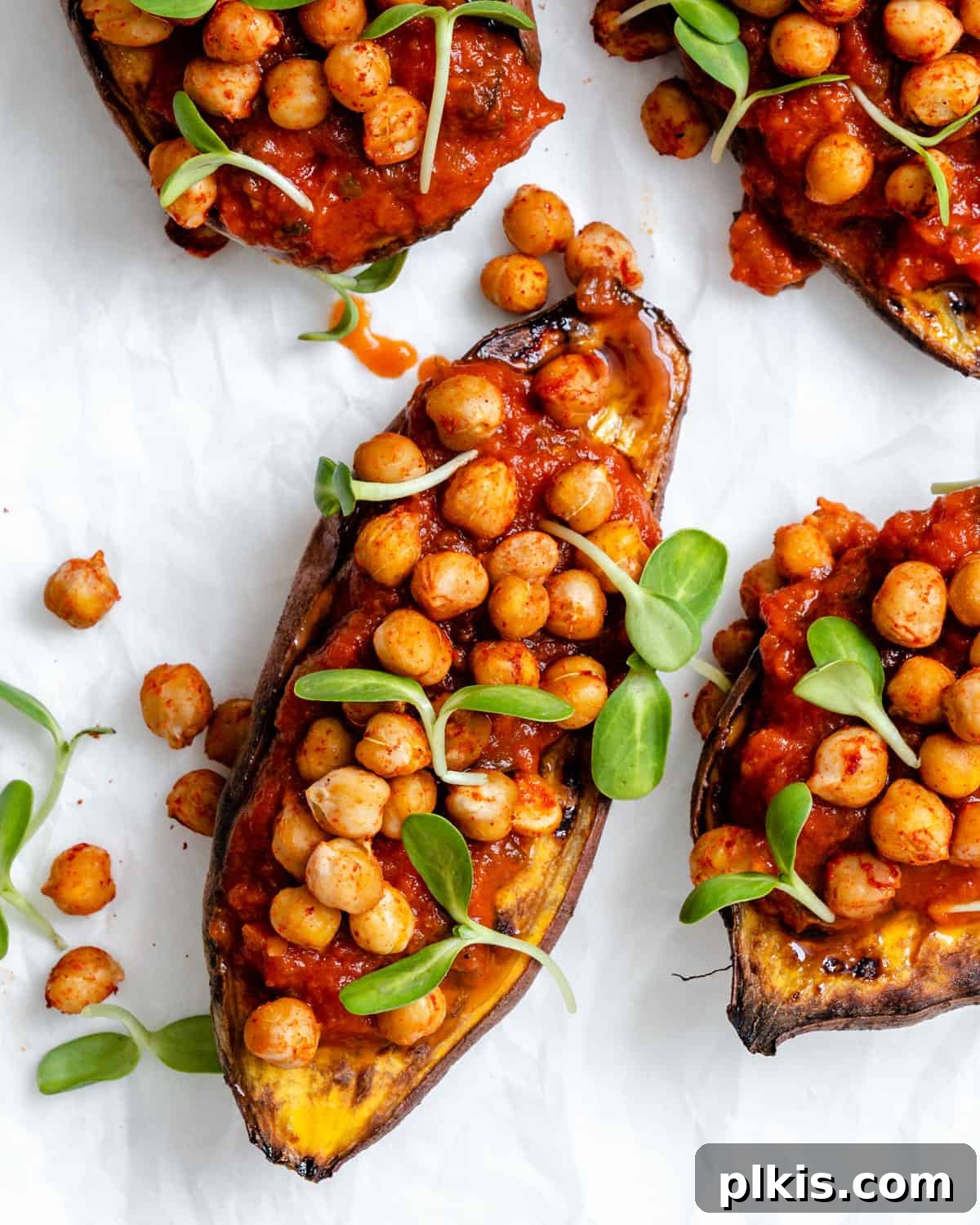 A close-up shot of two beautifully assembled Chickpea Sweet Potato Boats, generously stuffed and garnished with fresh greens, ready to be enjoyed.