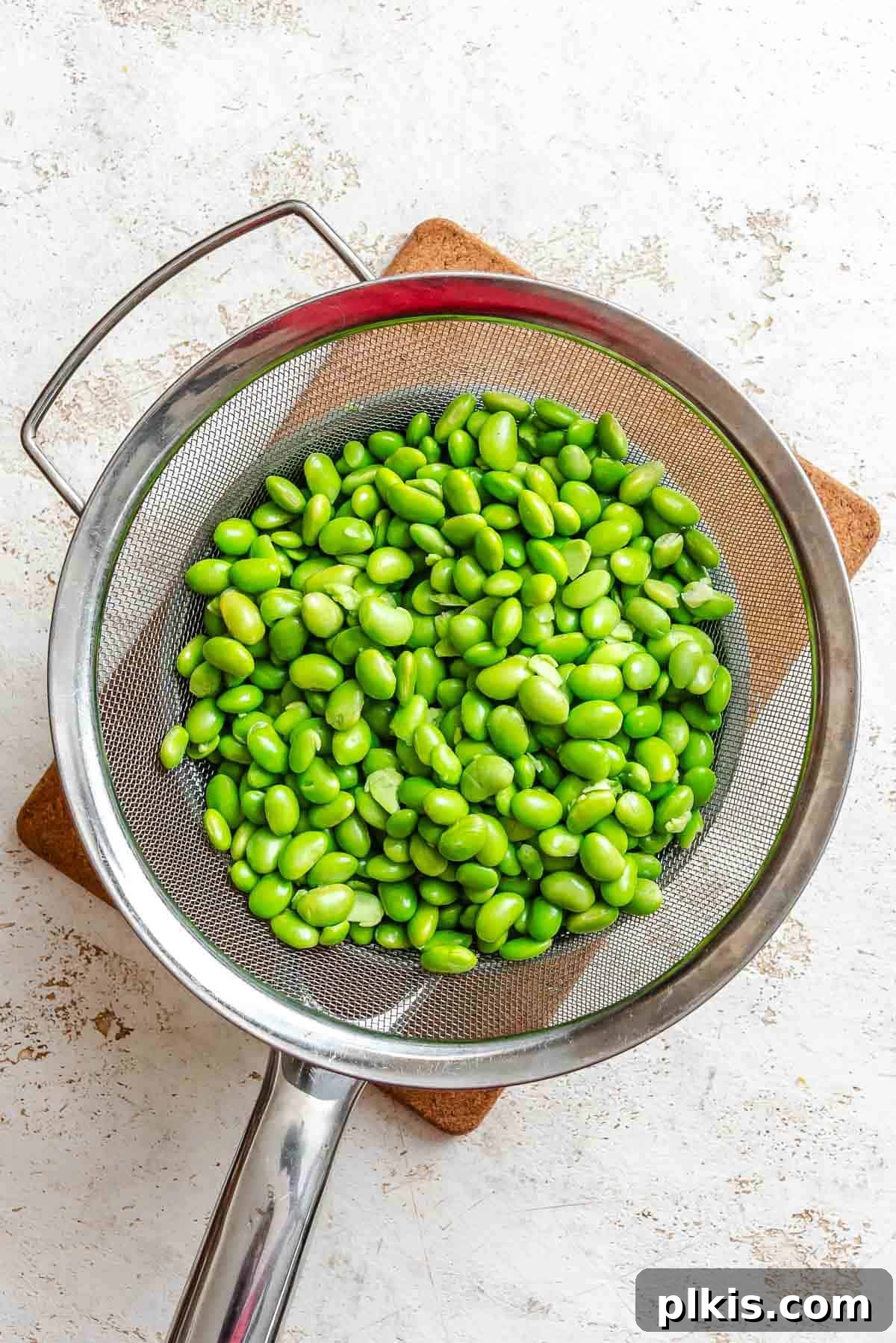 Vibrant Edamame Corn and Black Bean Salad 4 Process shot showing cooked edamame in a strainer, freshly drained and cooling.