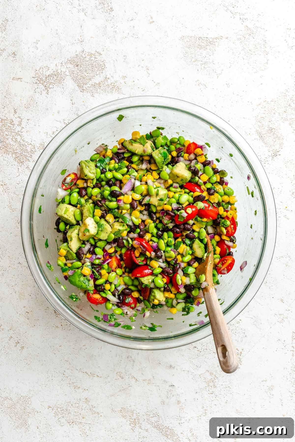Vibrant Edamame Corn and Black Bean Salad 6 Process shot showing the Edamame Salad ingredients being gently tossed together in a large bowl with dressing.