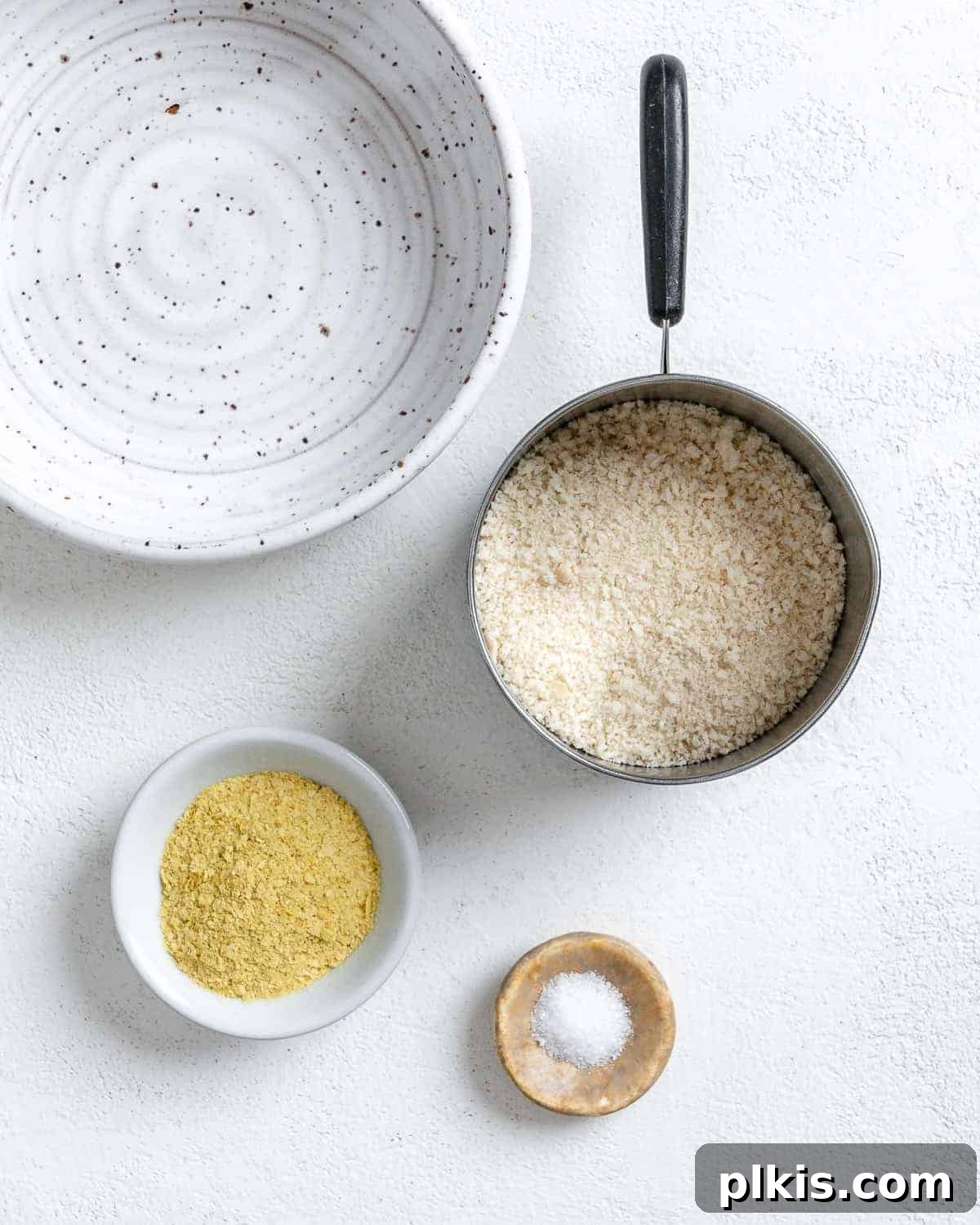 Breading ingredients (breadcrumbs, nutritional yeast, salt) measured out on a white plate, ready to be mixed.