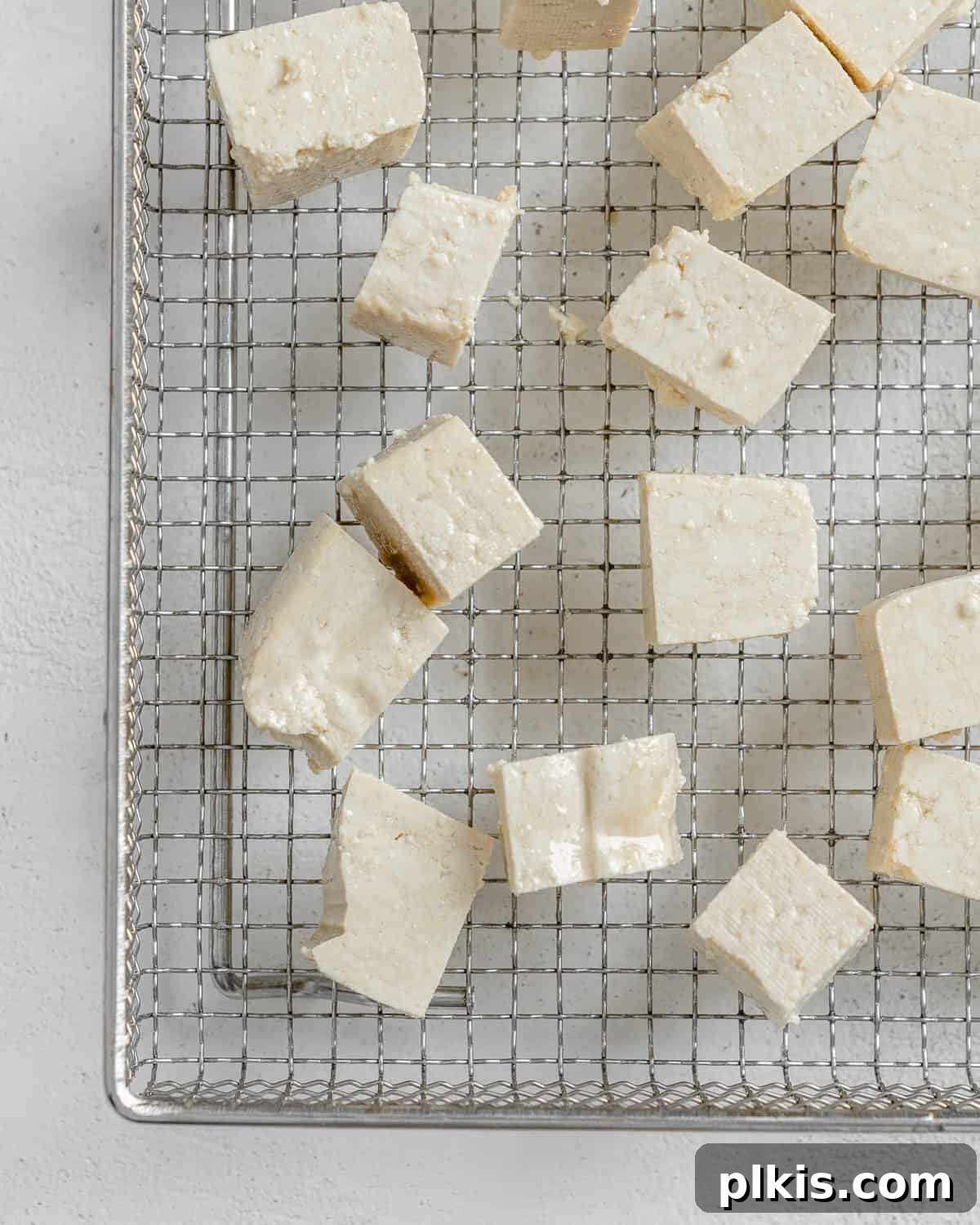 Zesty Tofu Tacos 5 Process shot showing cubed tofu arranged on a wire rack on a baking sheet, ready to be baked and dried out slightly, an important step for texture.