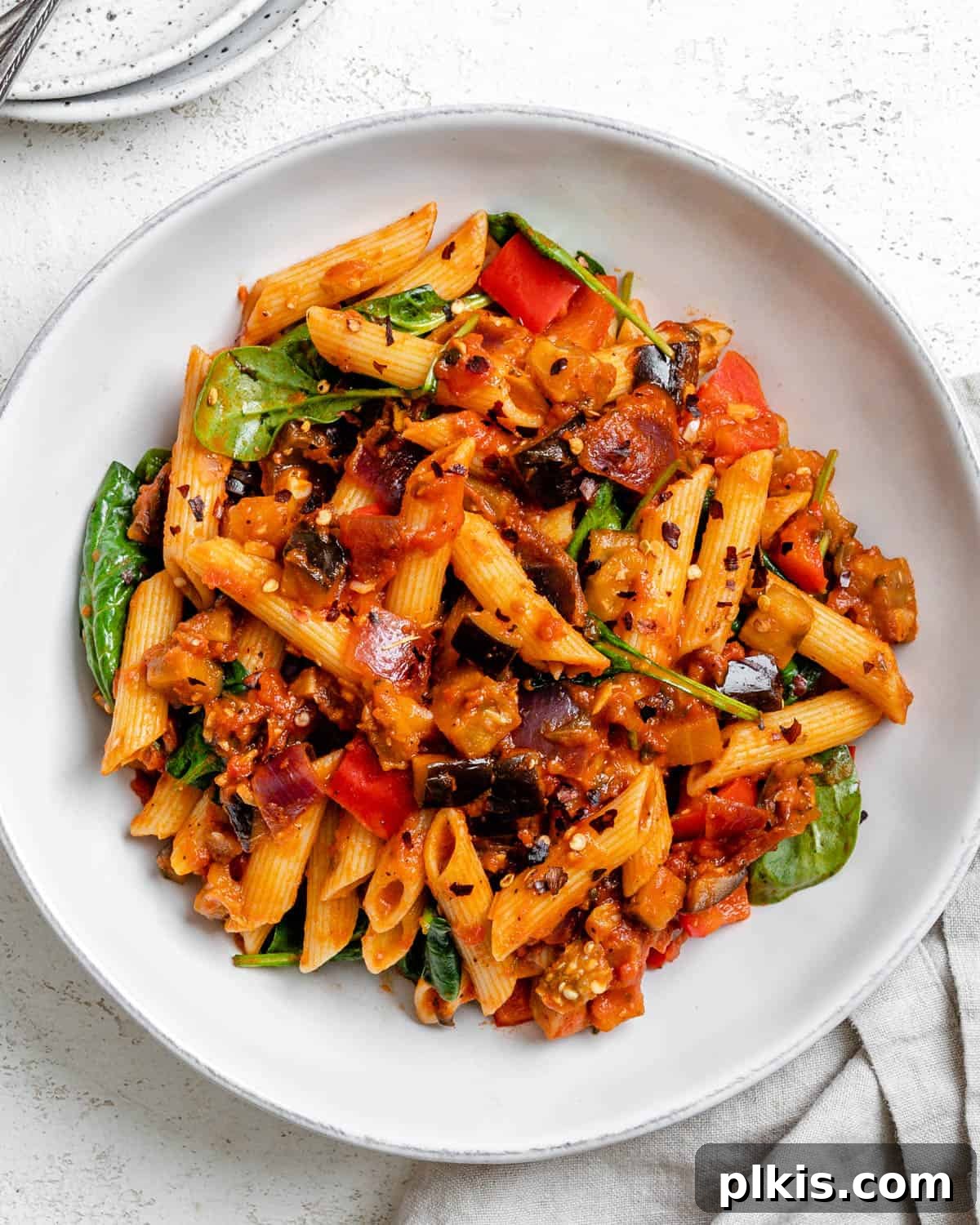 Effortless Eggplant Penne Alla Norma 2 Delicious Easy Penne Alla Norma (Eggplant Pasta) on a white plate, garnished with fresh herbs.