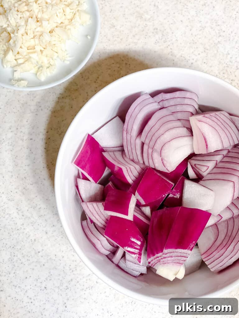 Effortless Eggplant Penne Alla Norma 4 Sliced onions and minced garlic in a bowl, ready for cooking.