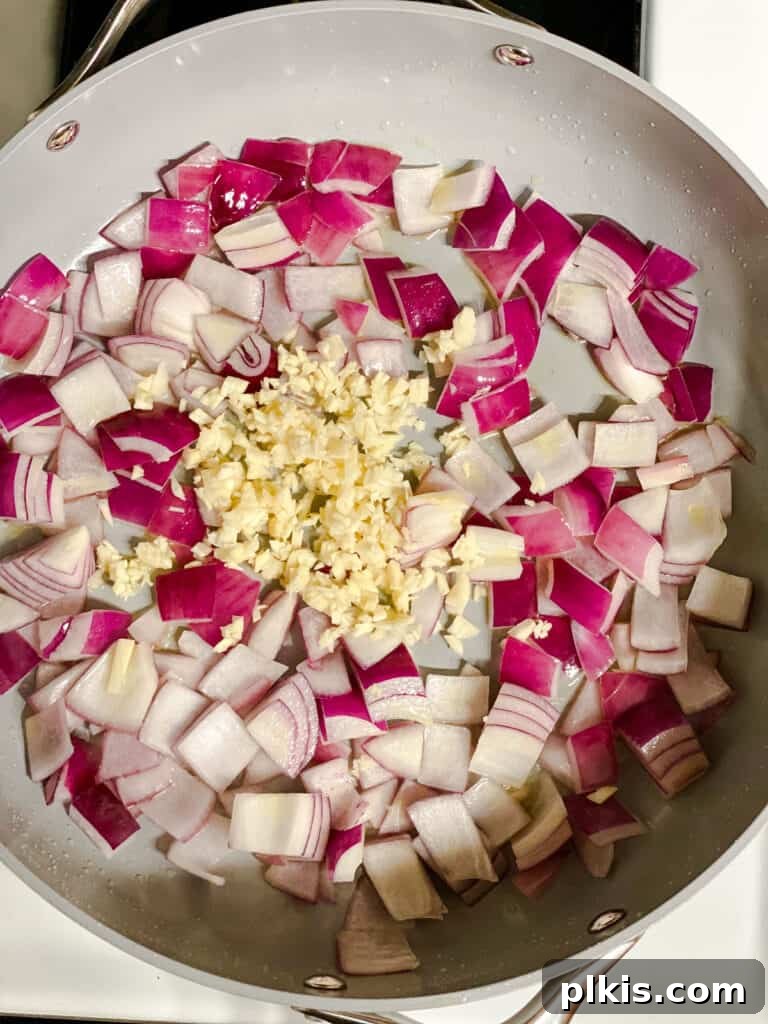Effortless Eggplant Penne Alla Norma 5 Onions and garlic being added to a hot pan with olive oil.