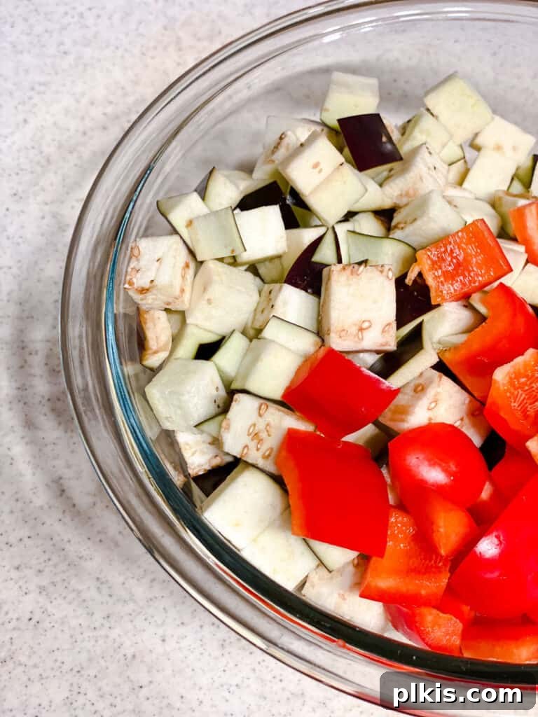 Effortless Eggplant Penne Alla Norma 6 Diced eggplant and red peppers in a bowl, ready to be cooked.