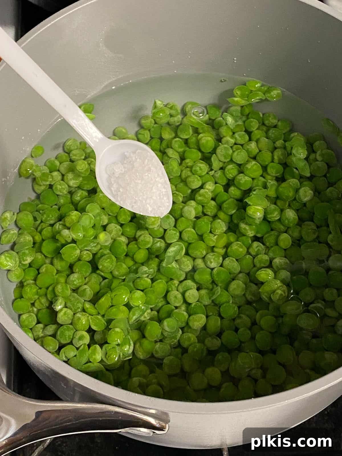 Effortless Creamy Peas with Golden Roasted Vegetables 5 process of adding salt to peas in a pot