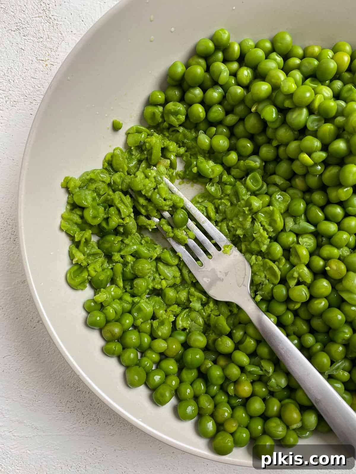 Effortless Creamy Peas with Golden Roasted Vegetables 7 process shot of mashing peas in a white dish
