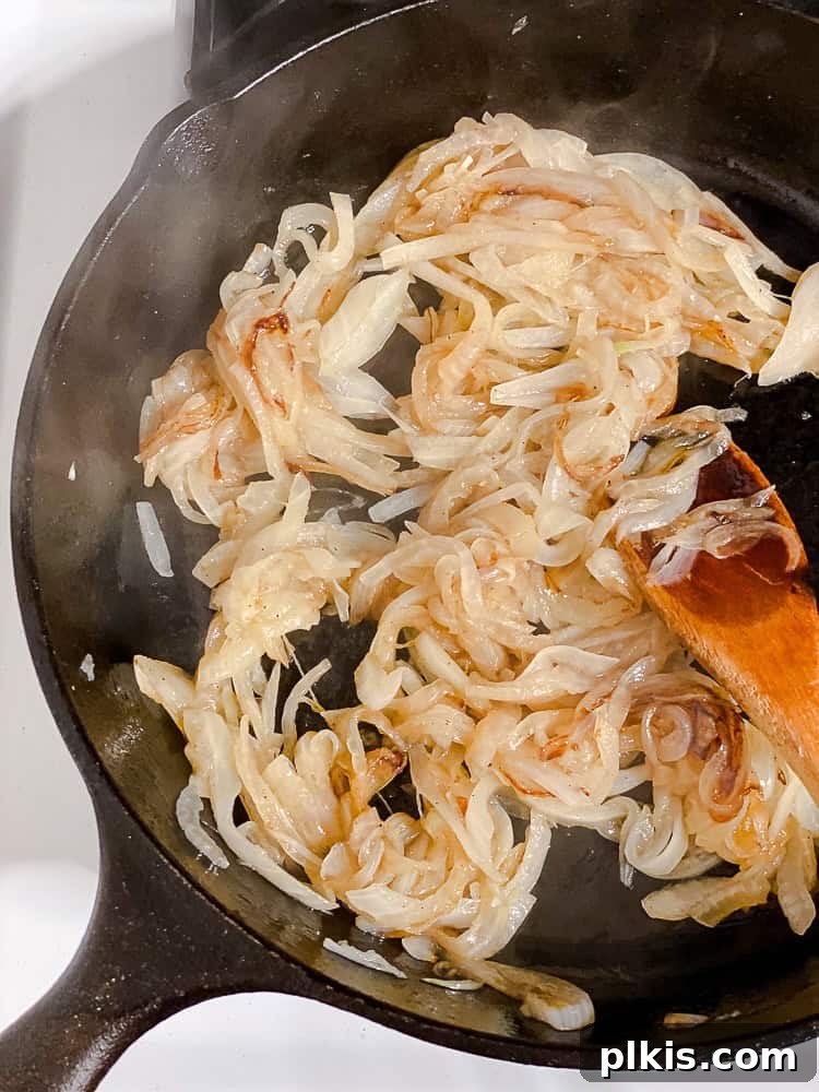 Savory Mushroom Stack 4 a wooden spoon stirring caramelized onions in a large black skillet.