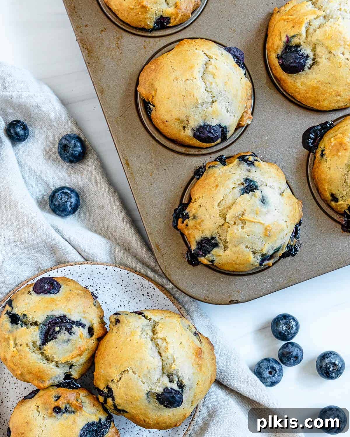 Effortless Vegan Blueberry Banana Delights 2 Freshly baked vegan blueberry banana muffins in a muffin tin and on a plate, ready to be enjoyed.