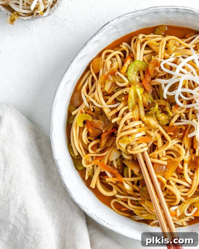 Easy Veggie Chow Mein A Delicious Plant-Based Bargain 2 completed bowl of Veggie Chow Mein in a white bowl against a white background with two chopsticks in the bowl