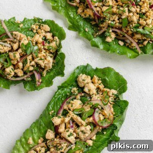 three completed larb salad servings against a white surface