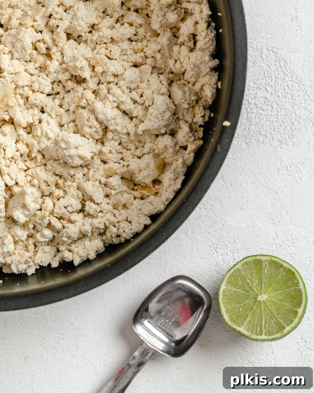 Vibrant Vegan Tofu Larb 4 Process shot of crumbled tofu sautéing in a pan against a white background.