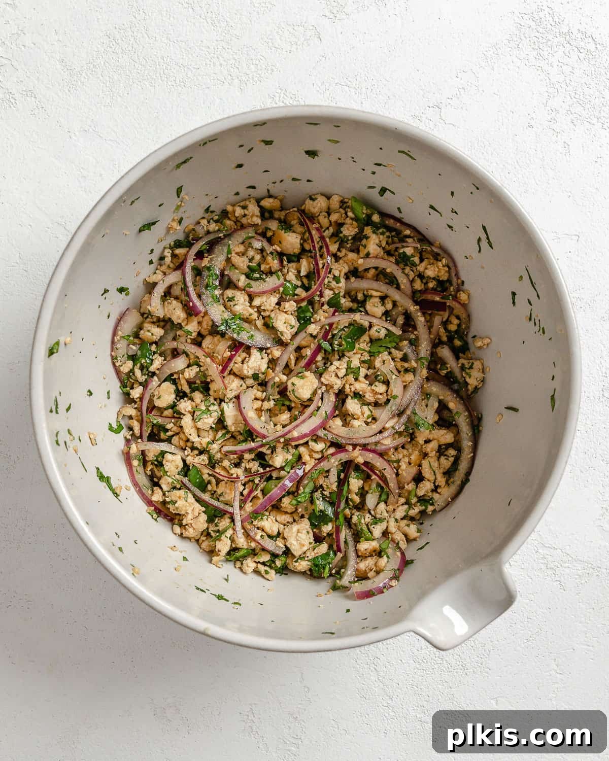 Vibrant Vegan Tofu Larb 7 Post-mixing of larb salad ingredients in a white bowl, ready to serve.