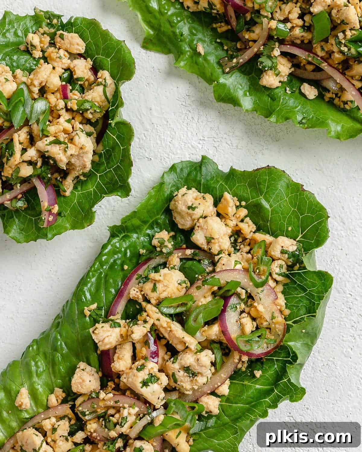 Vibrant Vegan Tofu Larb 10 Three completed larb salad servings with fresh lime and herbs against a white surface.