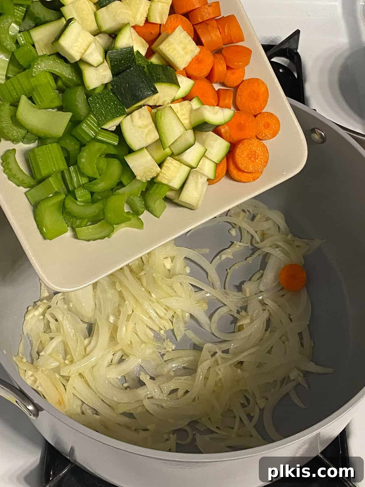 Wholesome Vegan Tofu Broth 6 Process shot illustrating a colorful mix of diced carrots, celery, and zucchini being added to the pot with the sautéed onions and garlic, creating a rich vegetable base for the Caldo de Tofu.