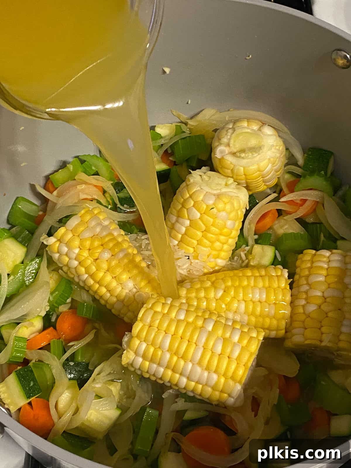 Wholesome Vegan Tofu Broth 8 Process shot of pouring vegetable broth (or water with bouillon) into the large pot, combining with the sautéed vegetables, corn, and tofu, to form the soup base for Caldo de Tofu.
