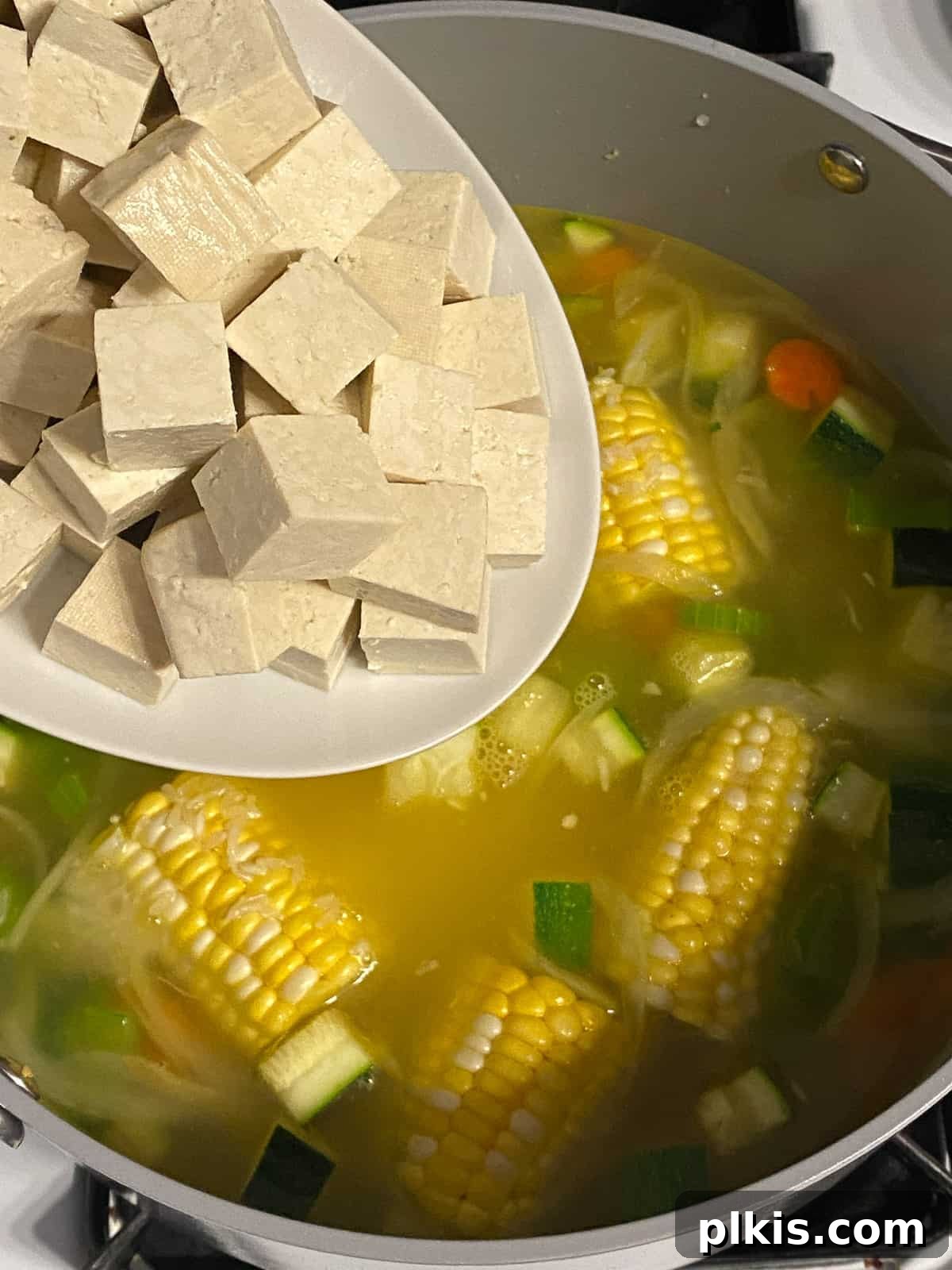 Wholesome Vegan Tofu Broth 9 Process shot showing diced extra firm tofu being gently added to the pot filled with vegetables, corn, and broth, ready to simmer and absorb the flavors of the Caldo de Tofu.