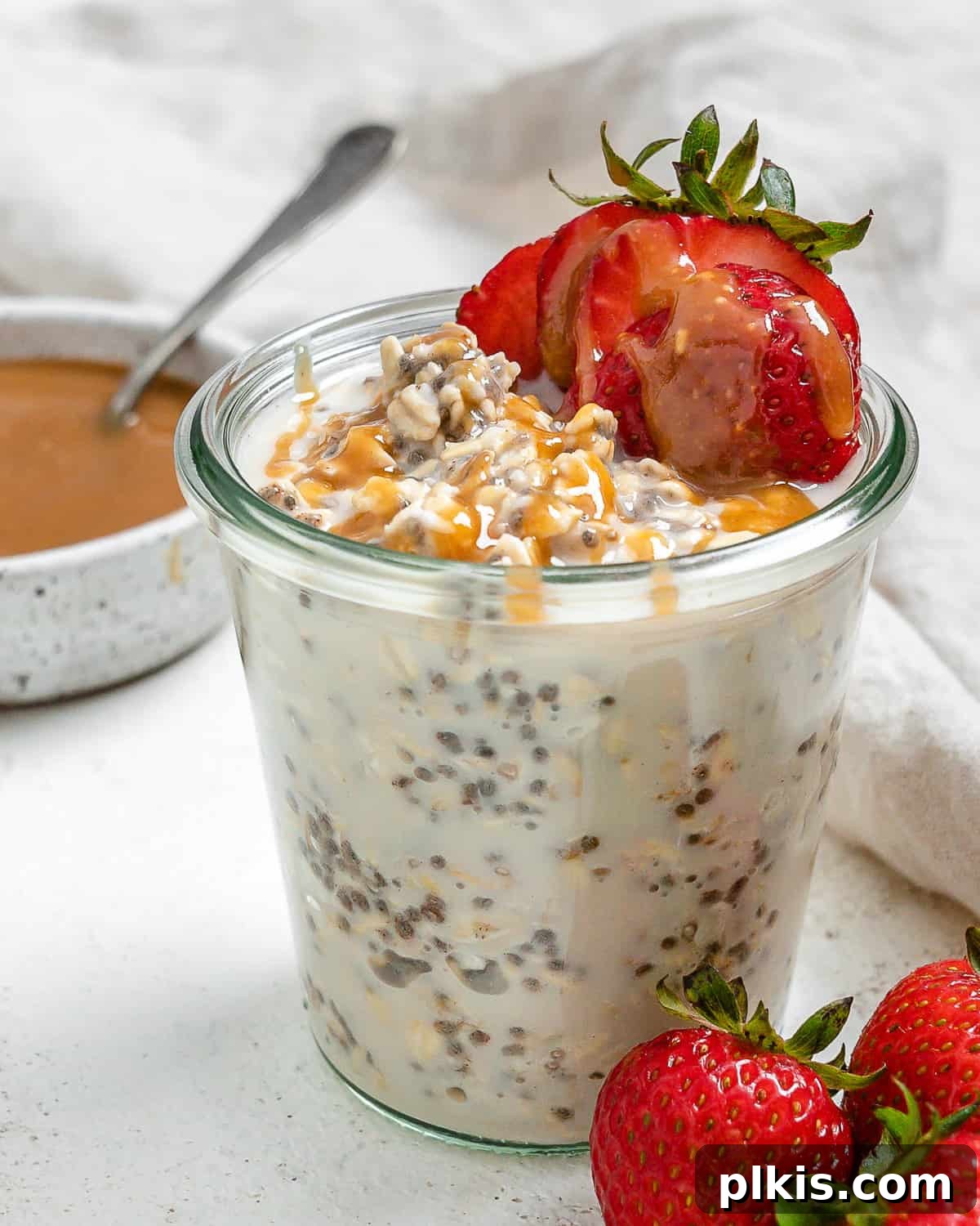 Decadent Salted Caramel Overnight Oats 2 completed Salted Caramel Overnight Oats in a clear cup with ingredients against a white background