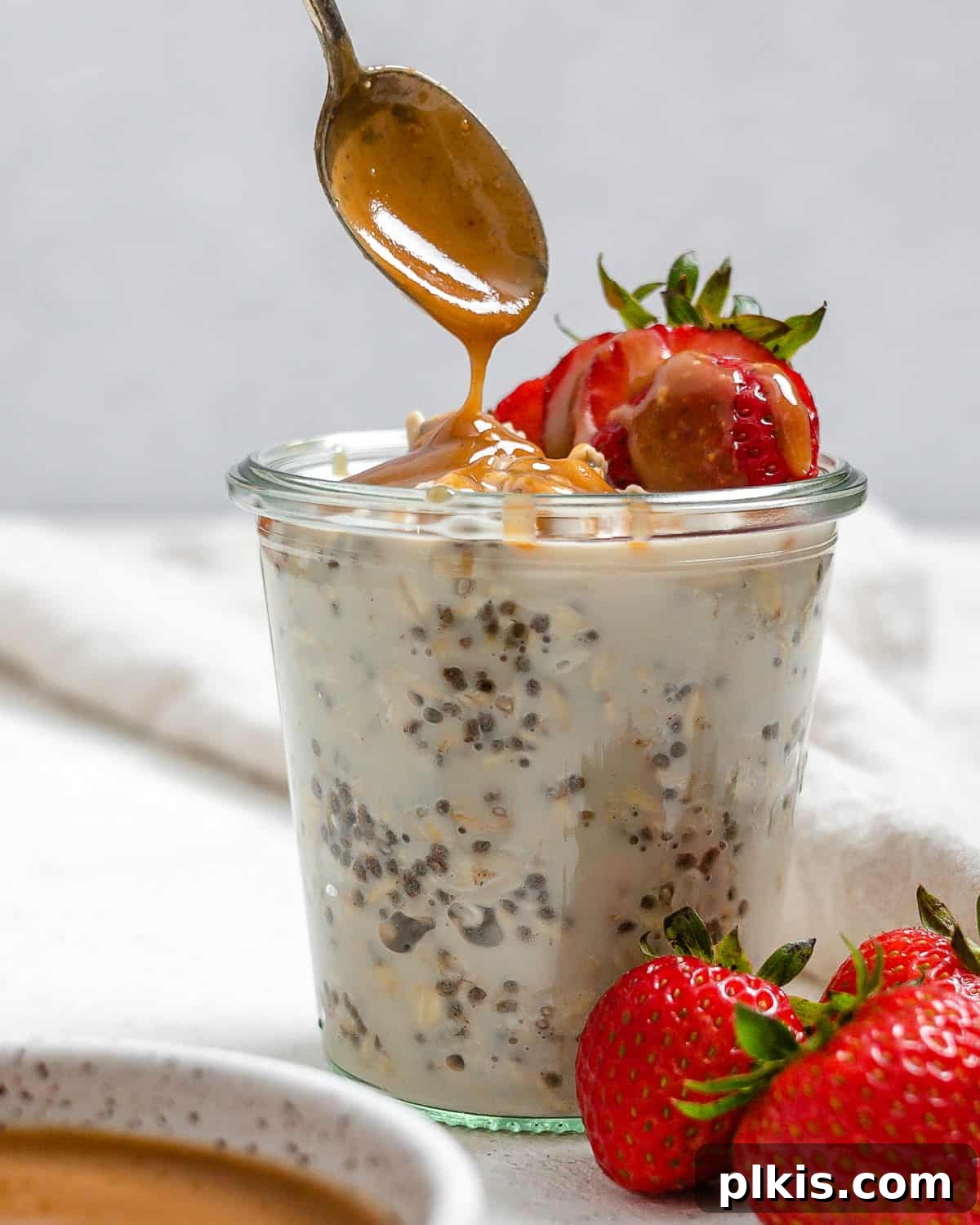 Decadent Salted Caramel Overnight Oats 13 completed Salted Caramel Overnight Oats in a clear cup with ingredients against a white background