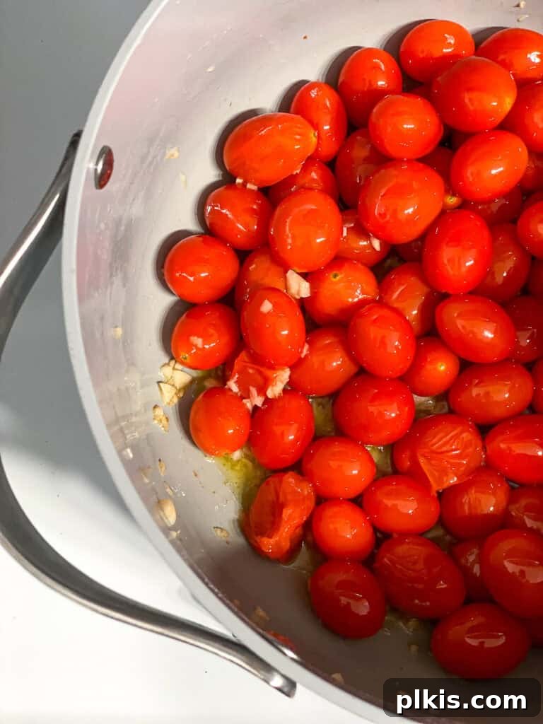 Cherry Tomato Basil Pasta in 15 Minutes 4 Process shot of cherry tomatoes cooking and softening in a pan with olive oil.