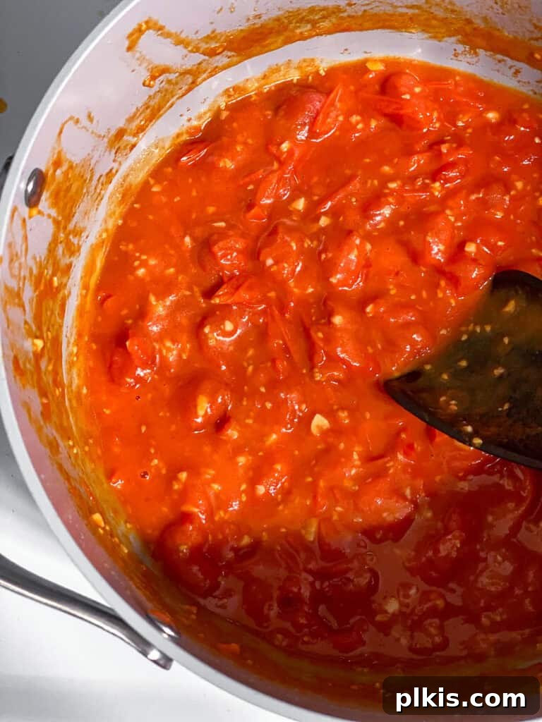 Cherry Tomato Basil Pasta in 15 Minutes 5 Process shot of the tomato and garlic sauce gently simmering in a pan, with some tomatoes mashed.