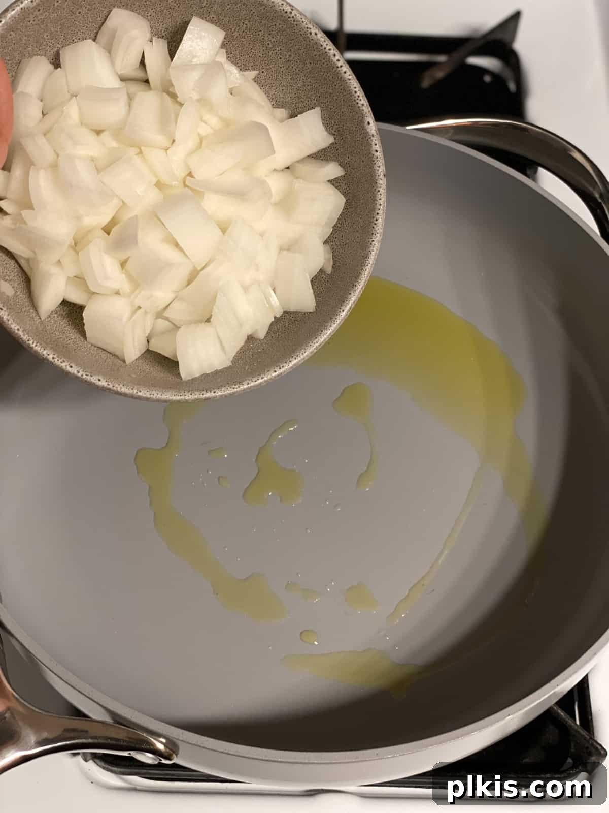 Vibrant Veggie Brown Rice Stir Fry 5 Process shot showing diced onions being added to a hot pan with oil, beginning the stir-fry process.