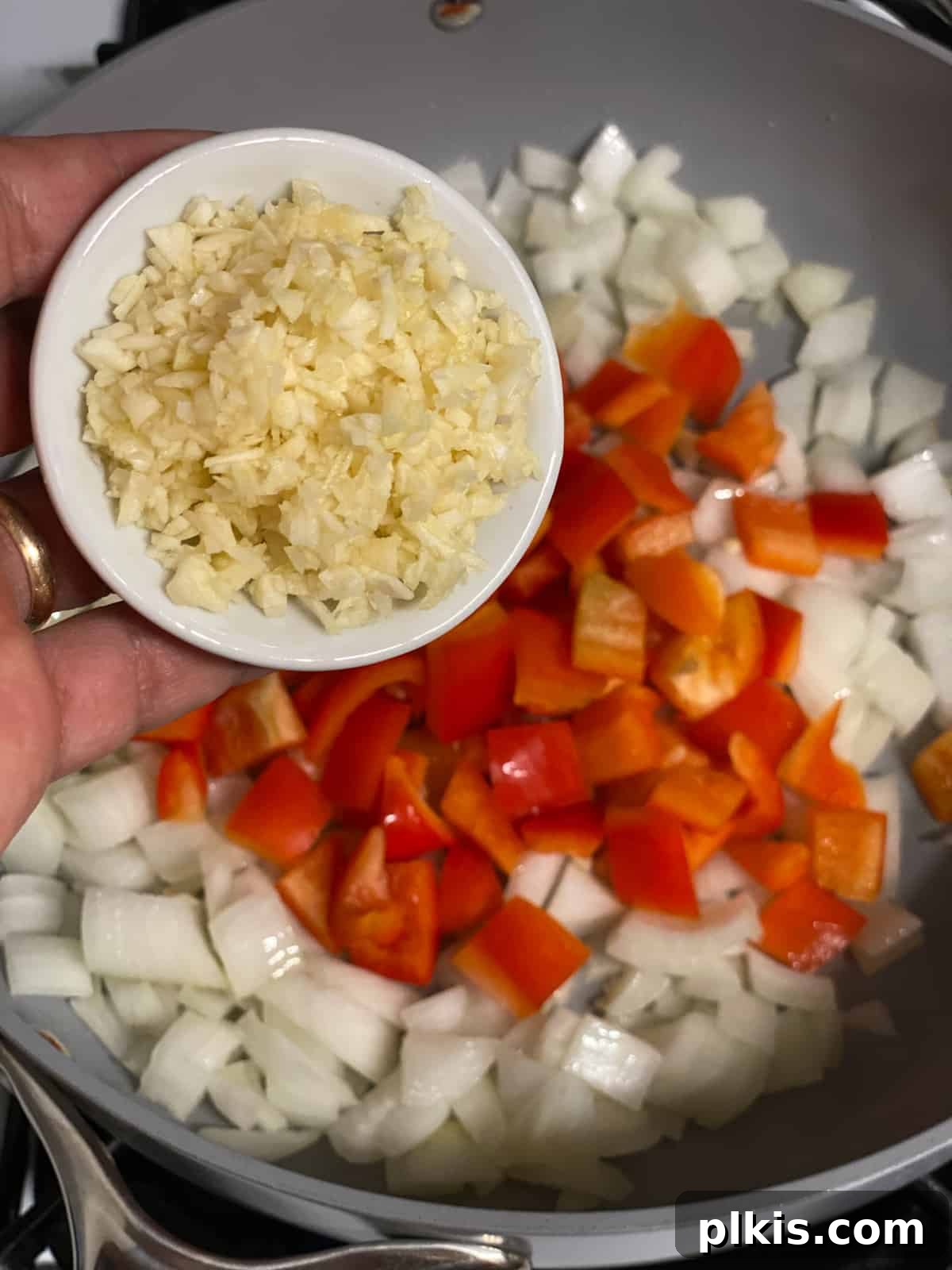 Vibrant Veggie Brown Rice Stir Fry 7 Process shot of minced garlic being added to the hot pan with vegetables, releasing its aromatic fragrance.