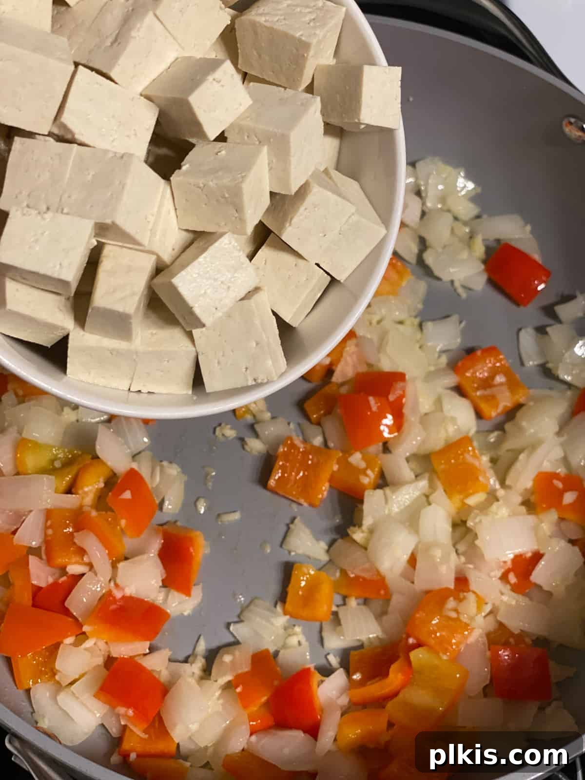 Vibrant Veggie Brown Rice Stir Fry 8 Process shot showing cubed extra-firm tofu being added to the pan with sautéed vegetables, ready to cook until golden.