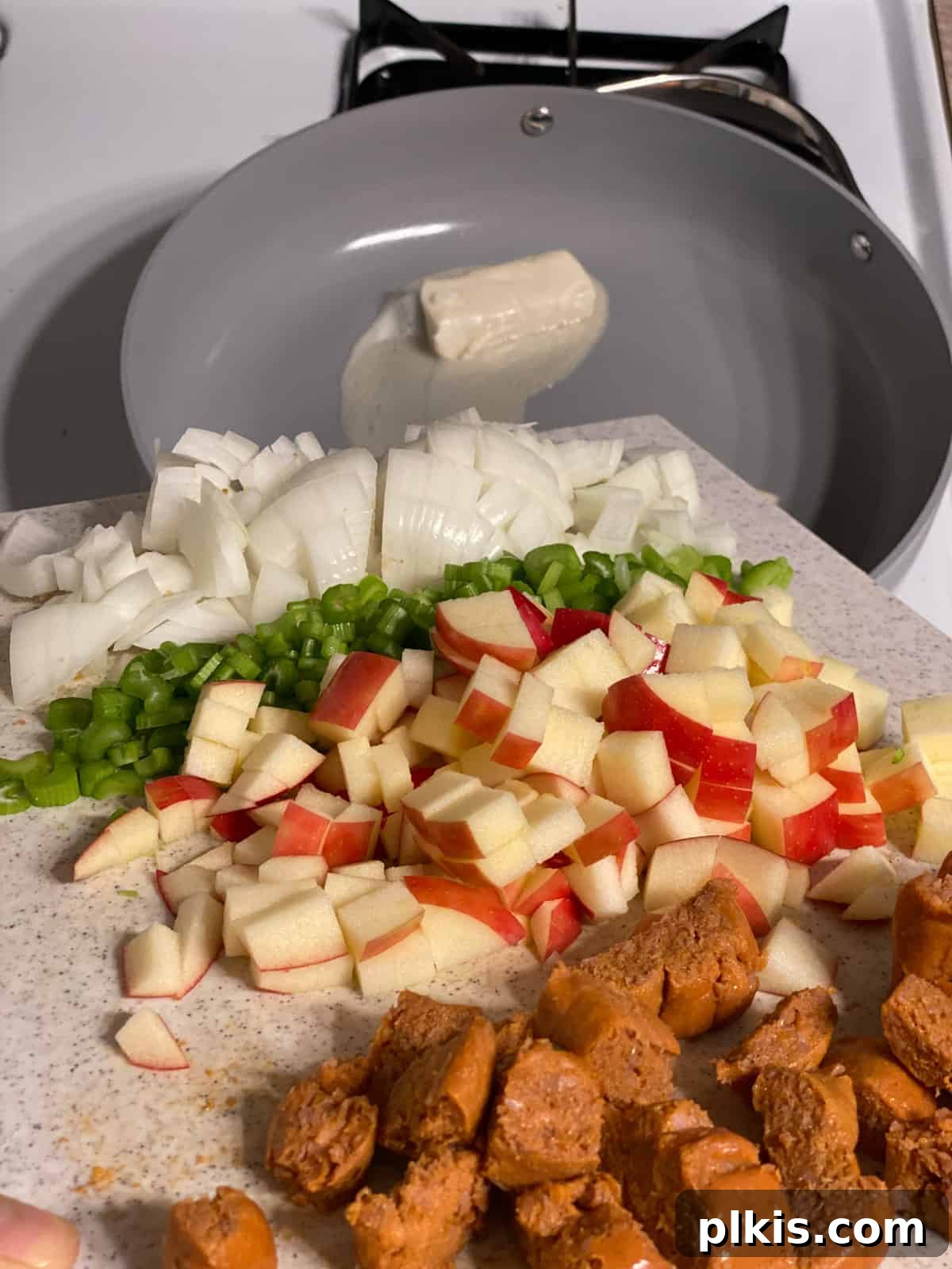 Ultimate Vegan Stuffing 5 Chopped onions, celery, apples, and vegan sausage being sautéed in a large skillet with melted vegan butter.