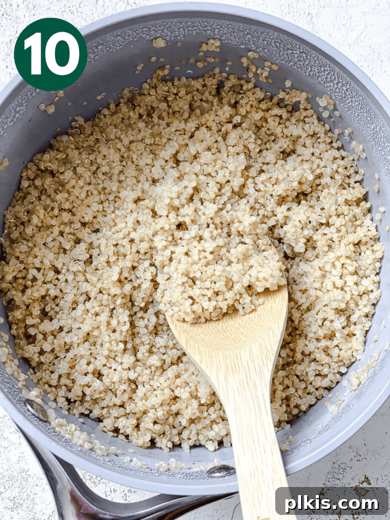 Roasted Sweet Potato Quinoa Power Bowl 13 Process shot showing fluffy, cooked quinoa being stirred in a bowl.