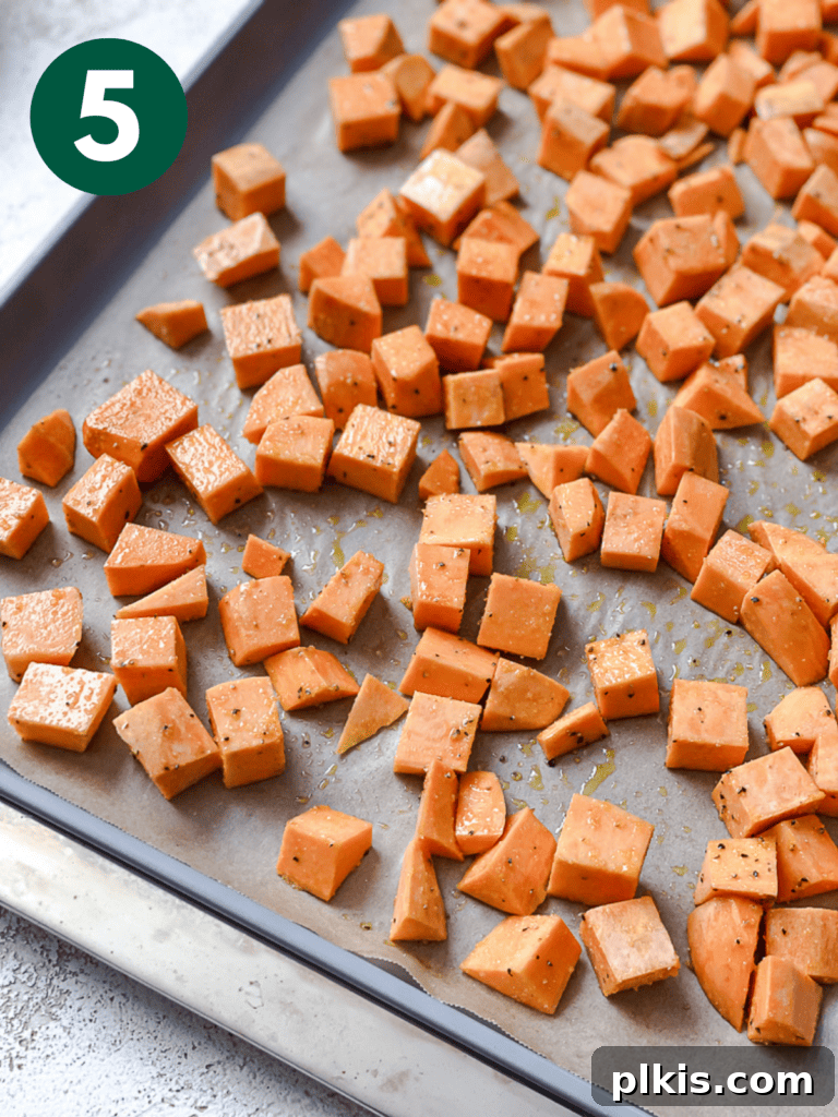 Roasted Sweet Potato Quinoa Power Bowl 8 Process shot showing raw, diced sweet potatoes seasoned and ready for roasting on a baking sheet.