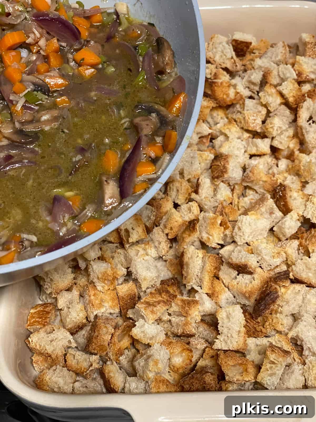 Simple & Savory Mushroom Stuffing 13 process of adding veggie broth mixture to pan of bread